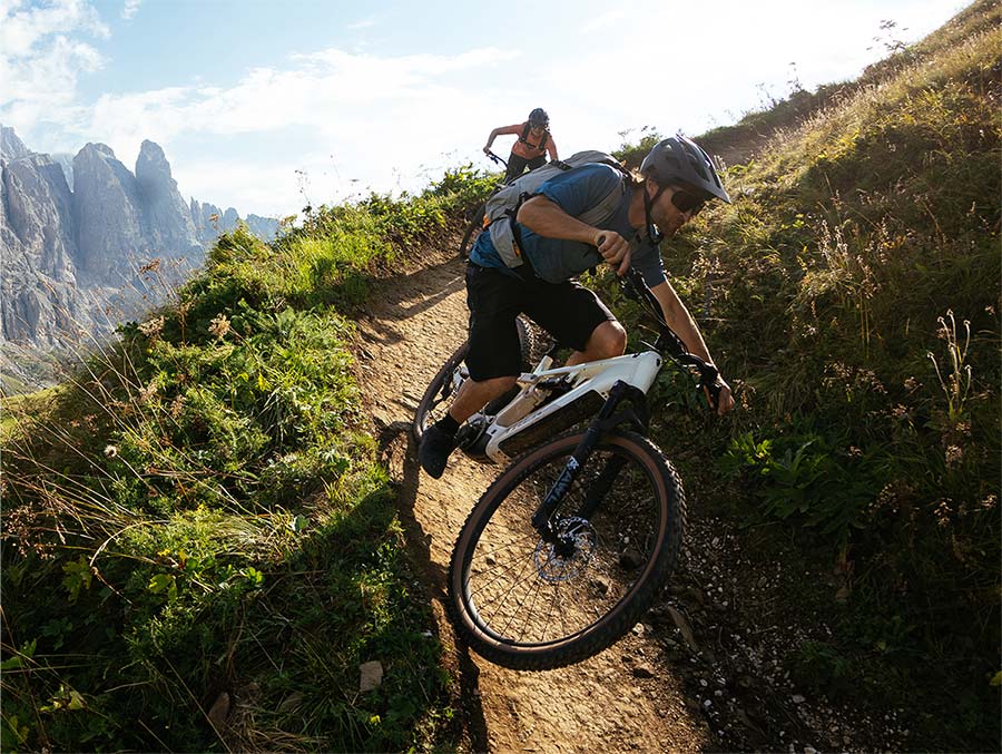 Cyclists wearing helmets while riding bikes on dirt trail