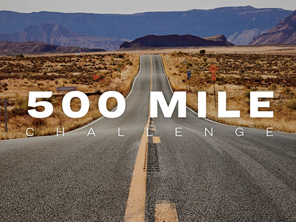 The words, '500 MILE CHALLENGE' overlaying paved road leading to mountains