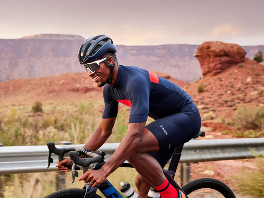 Cyclist wearing helmet and sunglasses while riding bike with mountains in background