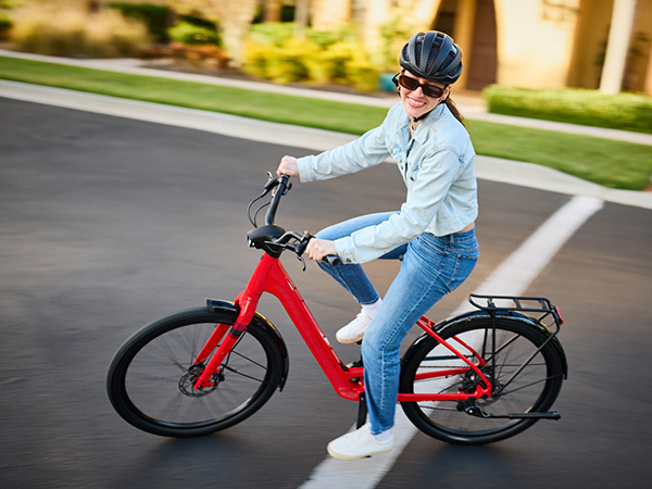 Cyclist wearing helmet and sunglasses while riding e-bike on paved road