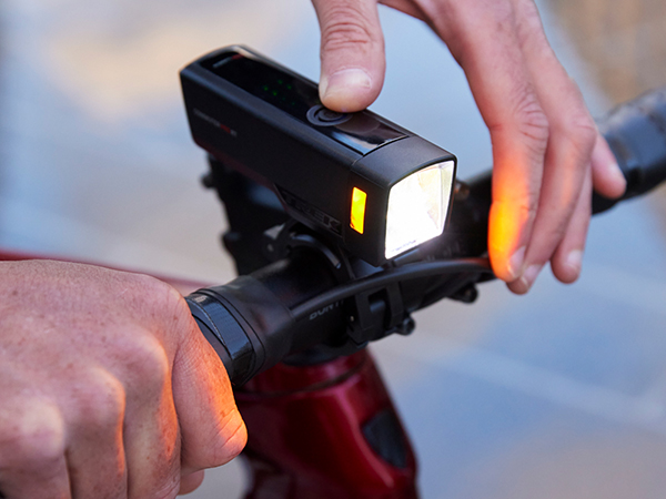 Close-up of cyclist turning on front bike light mounted to handlebar