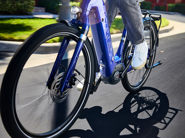 Close-up of bike frame with cyclist riding it on paved road