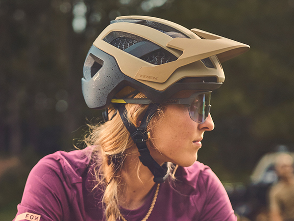 Cyclist wearing mountain bike helmet and sunglasses with tall trees in background