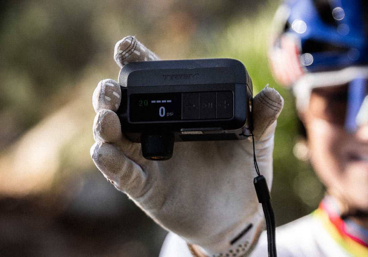 Cyclist wearing helmet and sunglasses while holding up Trek Air Rush Electric pump