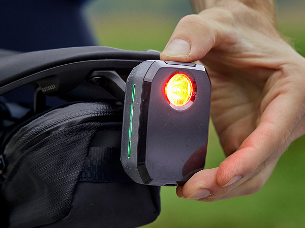 Cyclist turning on CarBack radar rear bike light mounted underneath saddle on bike