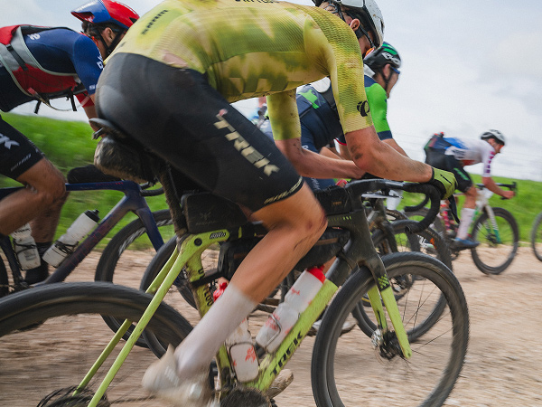 Group of cyclists wearing helmets while racing bikes on gravel road