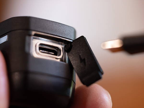 Cyclist pluggling USB-C cable into USB-C charging port of light