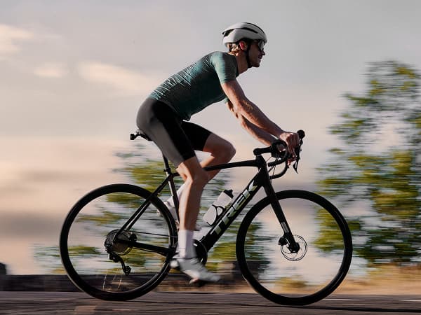 A person wearing a helmet rides a bicycle in motion blur