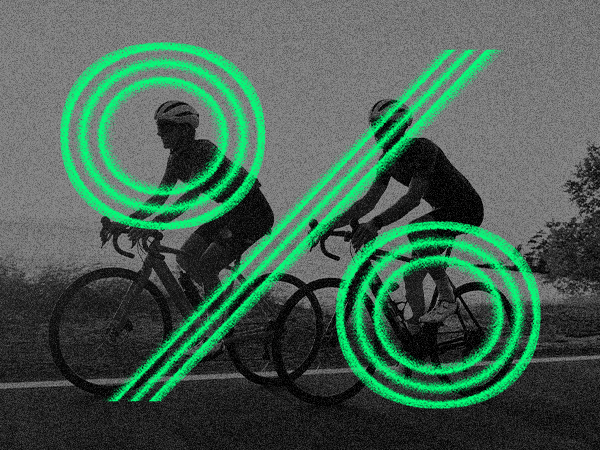 Two people ride a bicycle in motion blur with a large green percentage symbol overlaying the image
