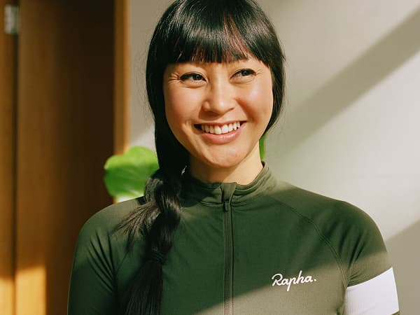Model wearing Rapha jersey with the 'Rapha' logo in large, white script lettering.