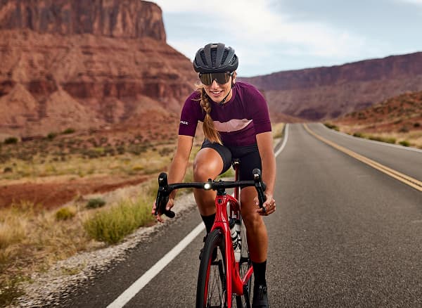 Lifestyle shot of two cyclists wearing helmets and sunglasses on road bikes