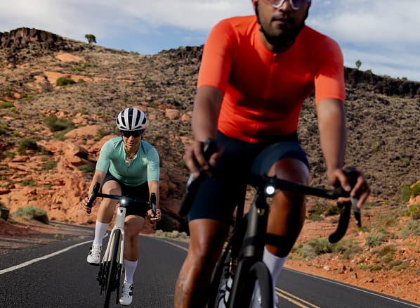 Lifestyle shot of two cyclists wearing helmets riding road bikes