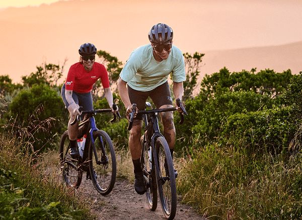 Lifestyle shot of two cyclists wearing helmets and sunglasses on gravel bikes