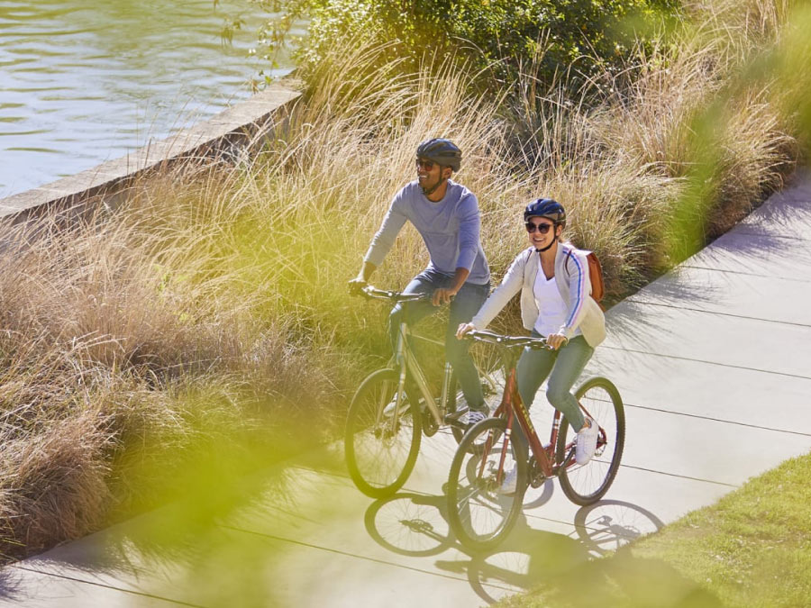 Cyclists wearing helmets while riding bikes on paved path