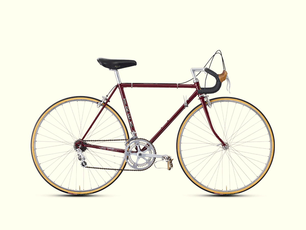 A classic Trek steel road bike from the 1970s on a cream background, representing the brand's material heritage