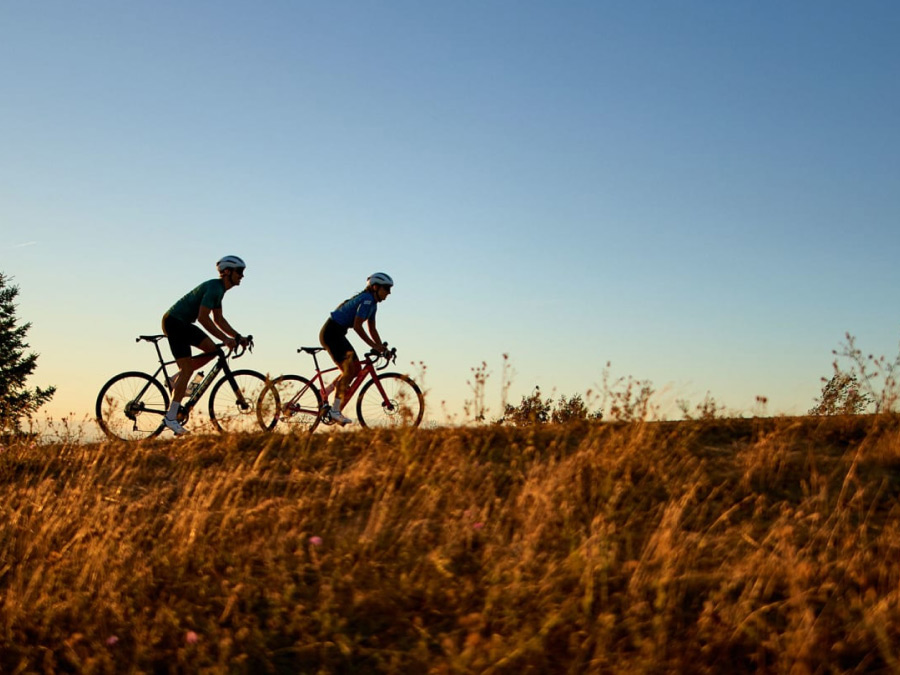 Cyclists wearing helmets while riding bikes on paved road
