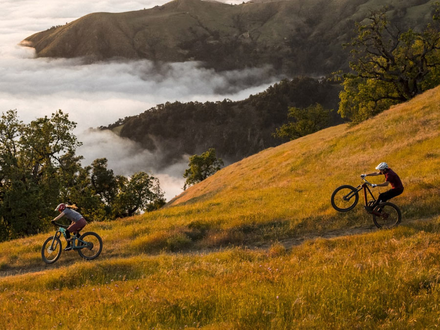 Cyclists wearing helmets while riding bikes on dirt path