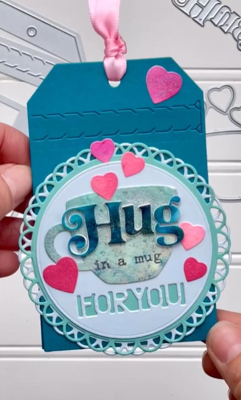 Zipper pull tab gift card tag with a teacup and "Hug in a mug for you" in teal and pink