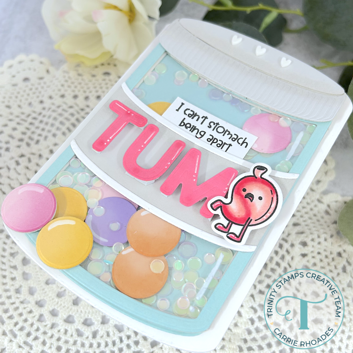 A medicine bottle-shaped card die with colorful pills and a phrase stating "I can't stomach being apart" and "TUM" on the label