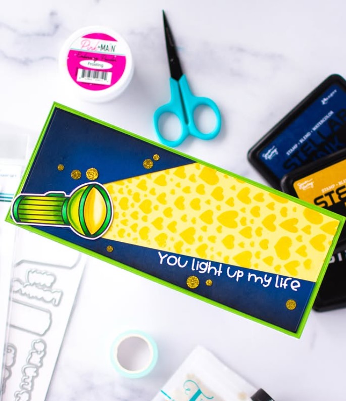 Slimline greeting card featuring a the Recharge flashlight set with the Beaming with Love stencil in shades of blue, yellow and green