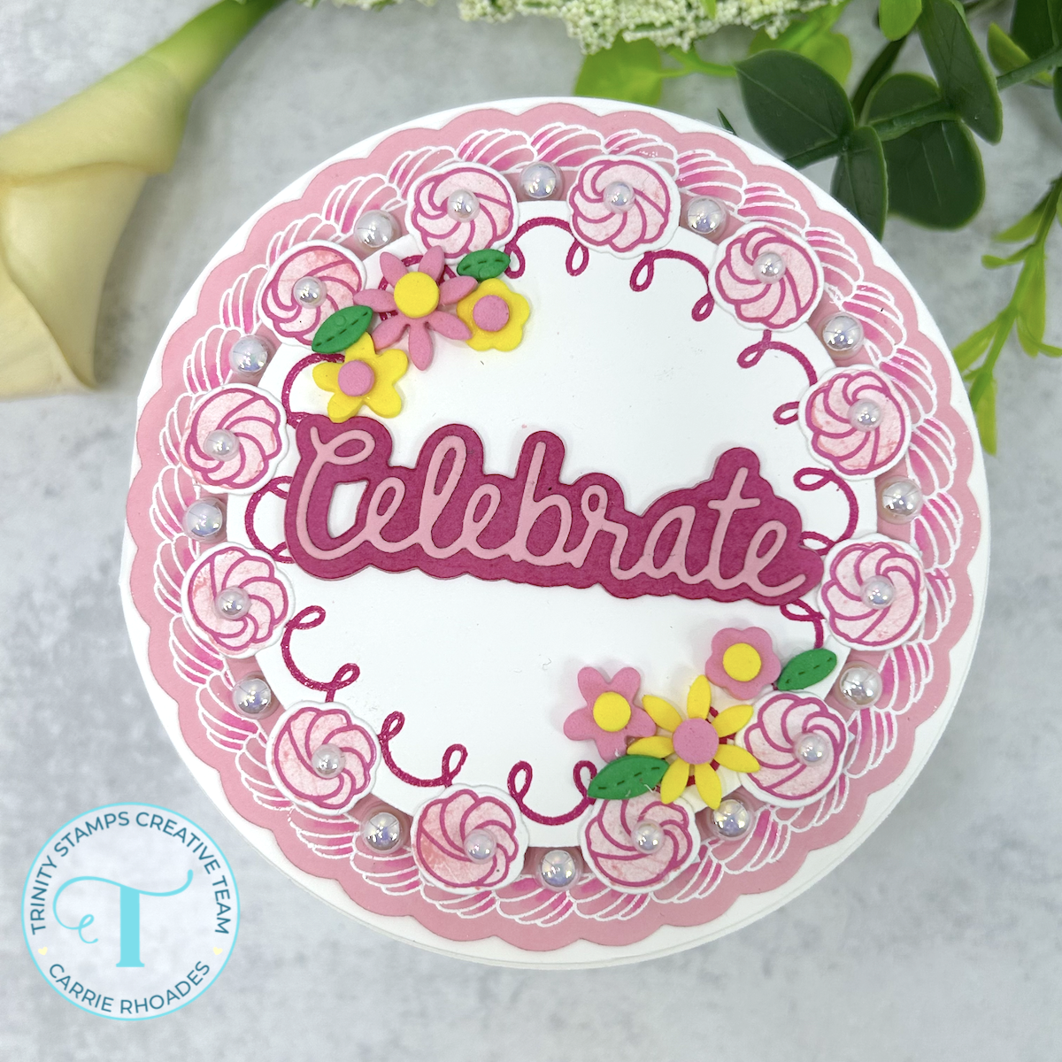 Round pink and white birthday cake-shaped greeting card with flower decorations and a "Celebrate" sentiment