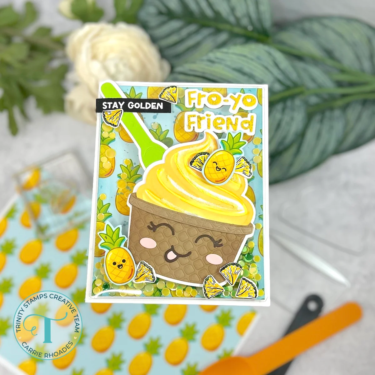 Yellow frozen yogurt with a pineapple theme, green spoon, brown smiley face cup. Message reads "stay golden / fro-yo friend"
