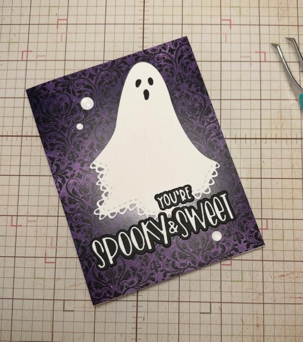 Dainty white ghost with delicate sheet detail on a dark purple brocade-themed background reading "You're Spooky & Sweet"