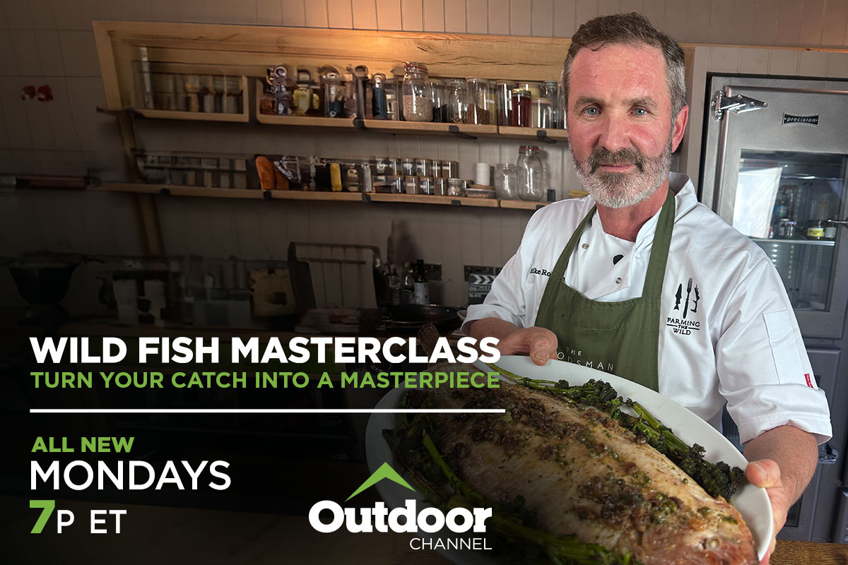 Chef standing in kitchen, holding a full fish meal 