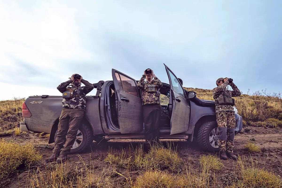 3 hunters in camo standing in front of tan truck