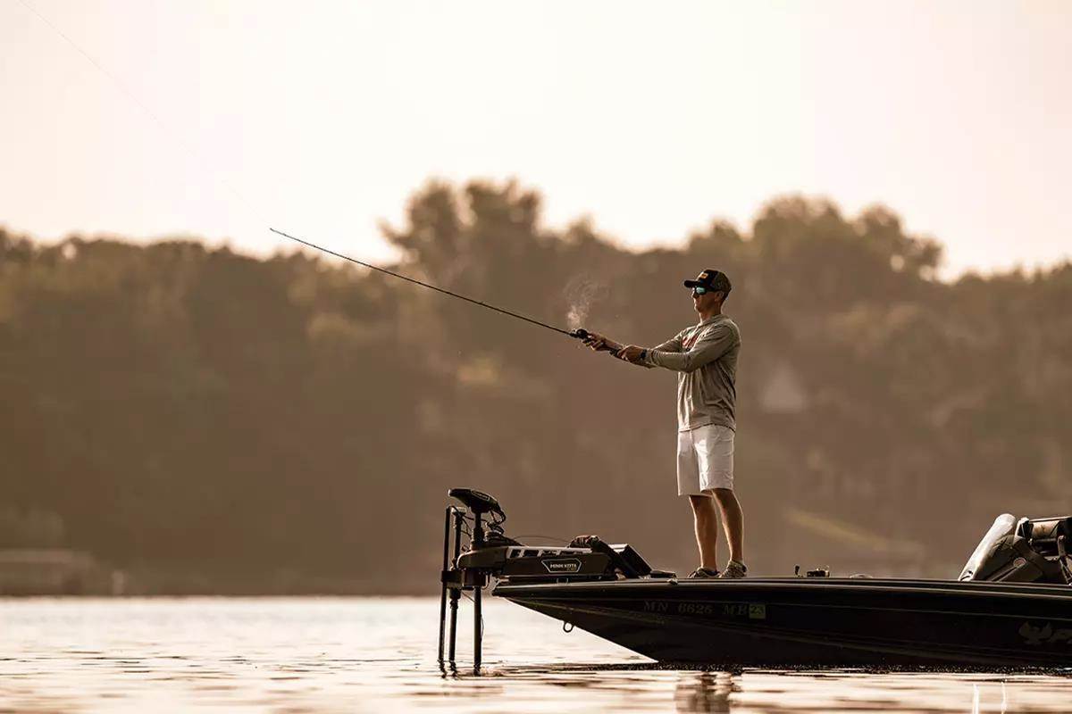 Man fishing in still waters off of a boat
