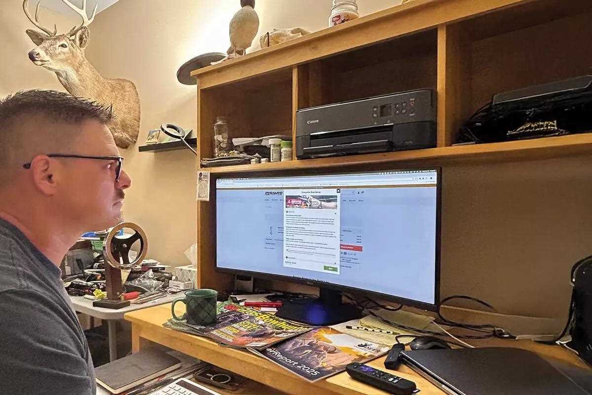 Man with glasses looking at large computer screen