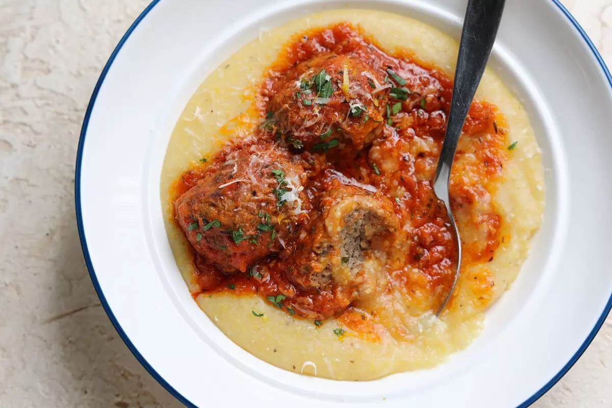 Delicious plate of huge, moist meatballs and light red sauce, in polenta