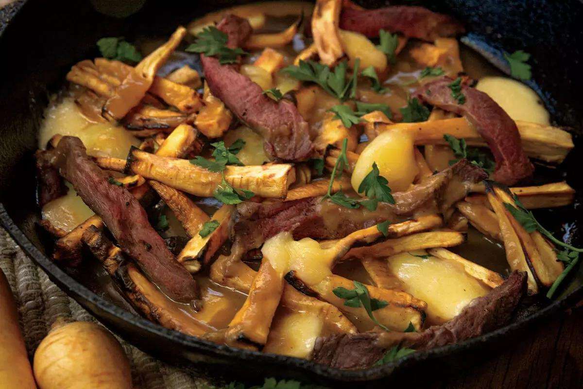 French fries, melted cheese, and elk displayed in black skillet