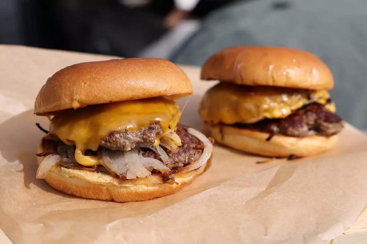 View of 2 delicious venison cheeseburgers on marble countertop
