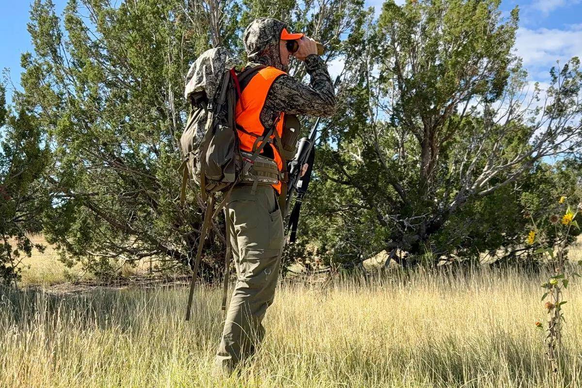 Hunter wearing backpack and looking through binoculars