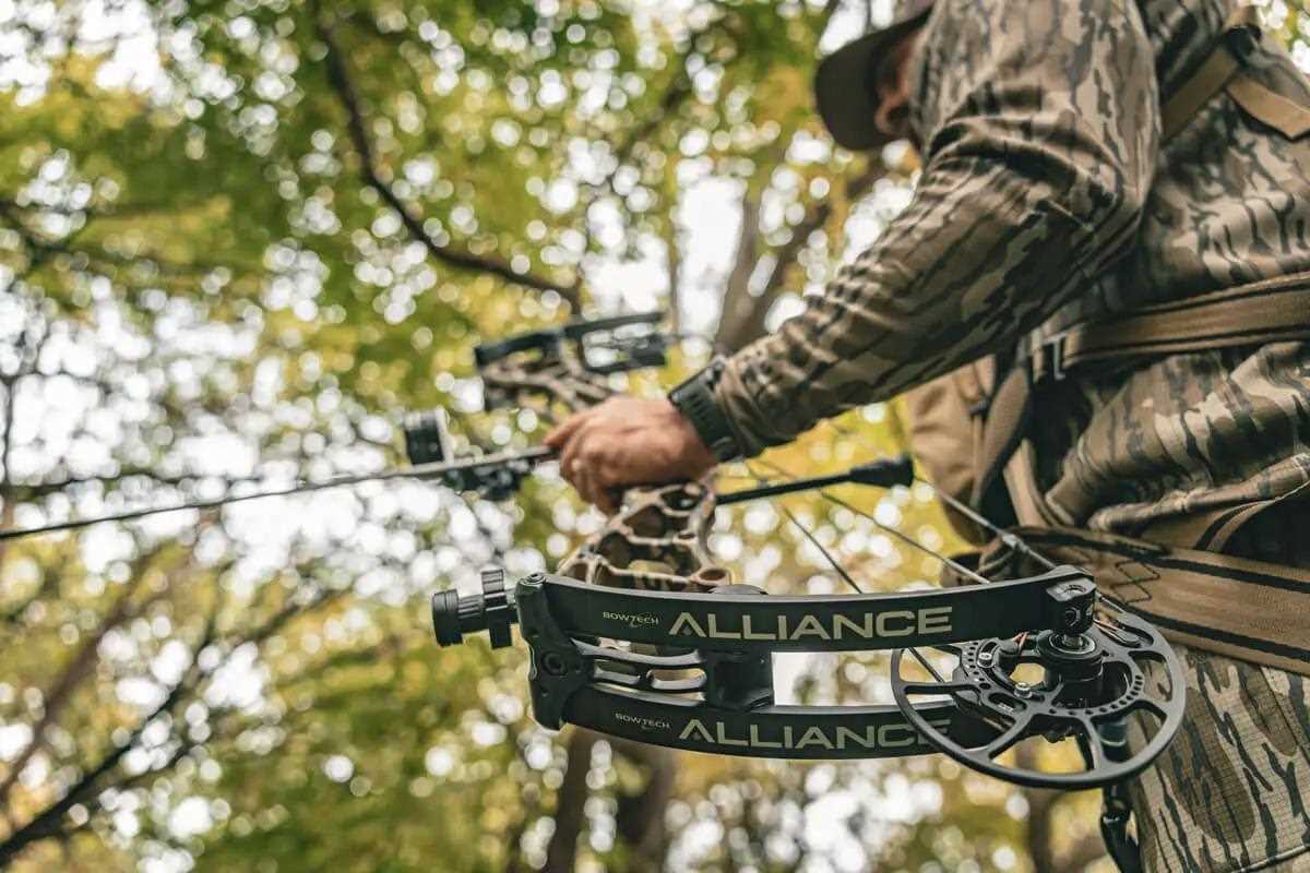 Man in camo setting up bow in woods