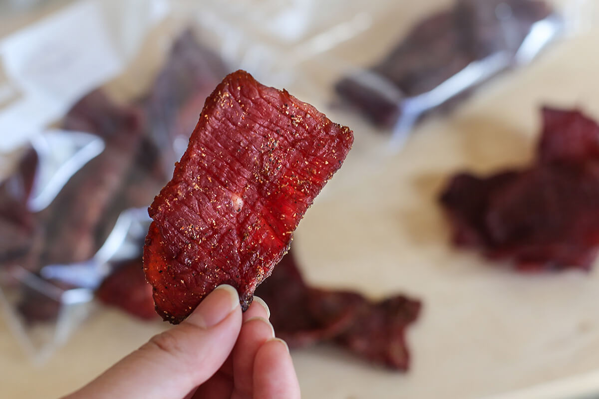 Hand holding square piece of jerky