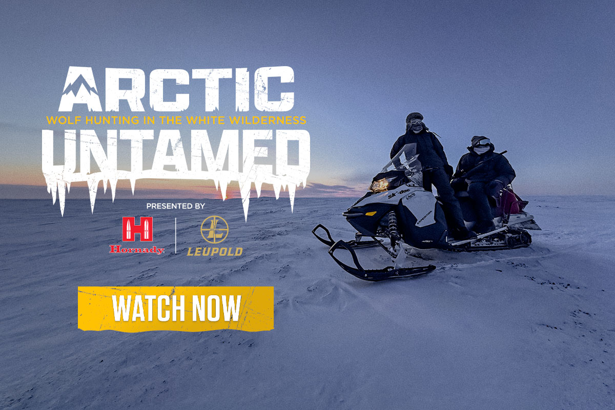 Two people on a snowmobile in the snow at night