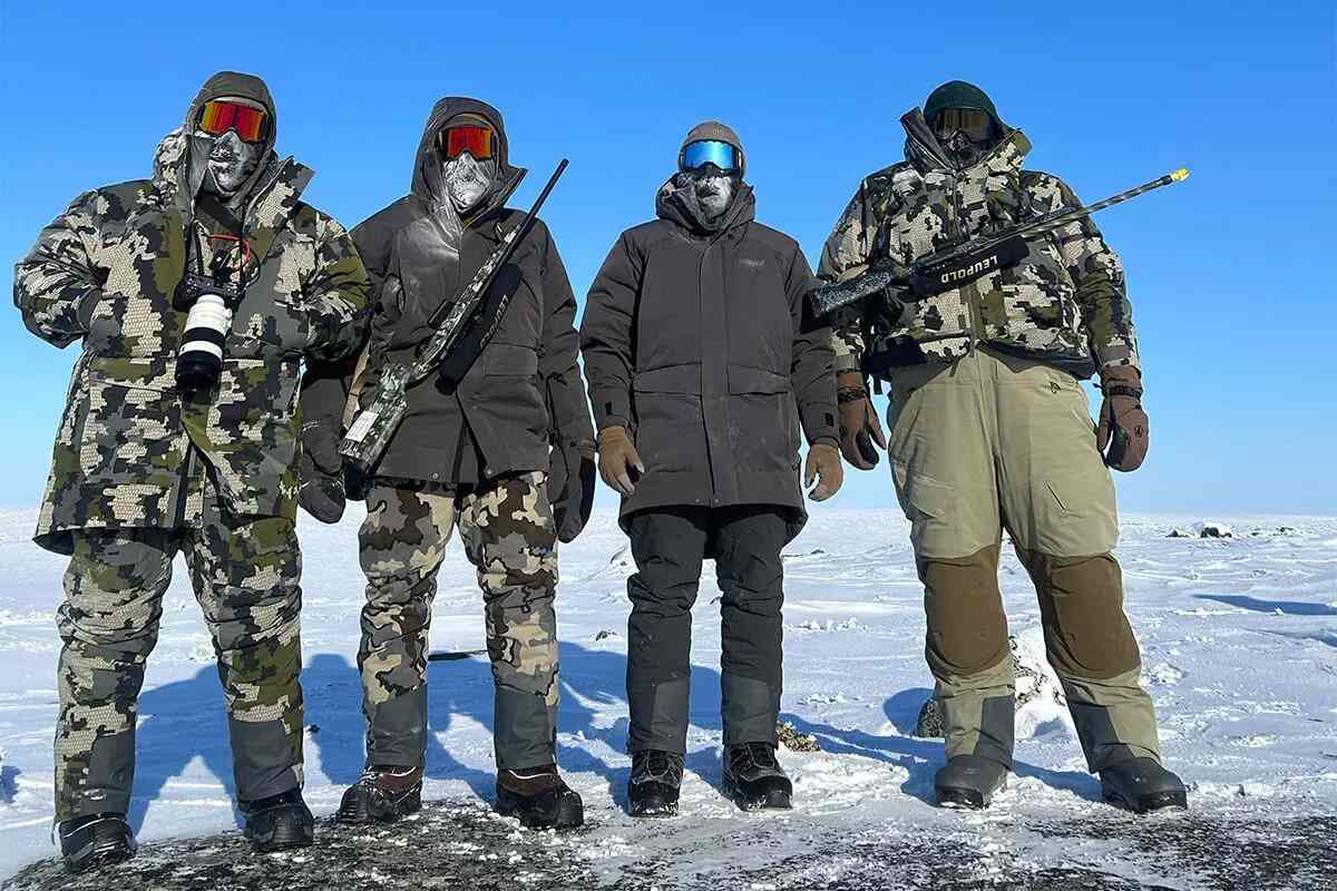 4 wolf hunters bundled up and armed in the Arctic