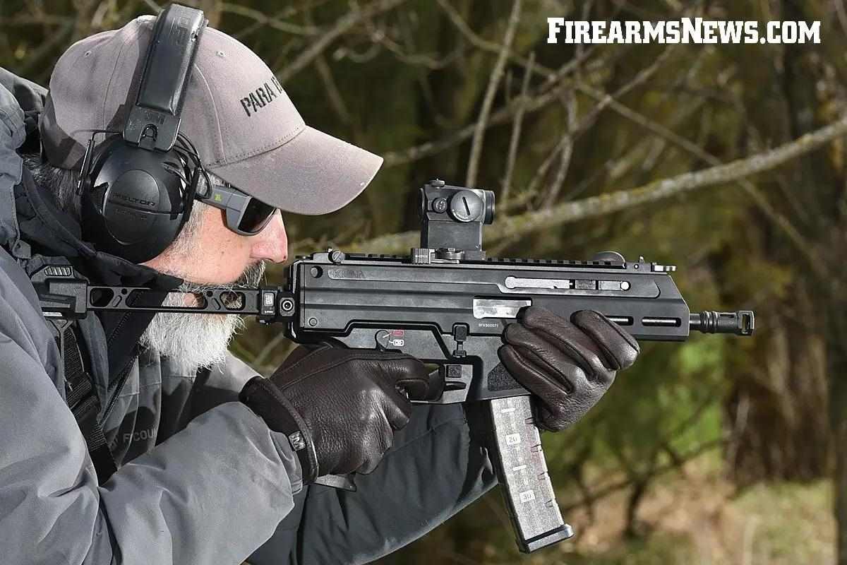 Man in shades and hoodie, aiming black carbine weapon