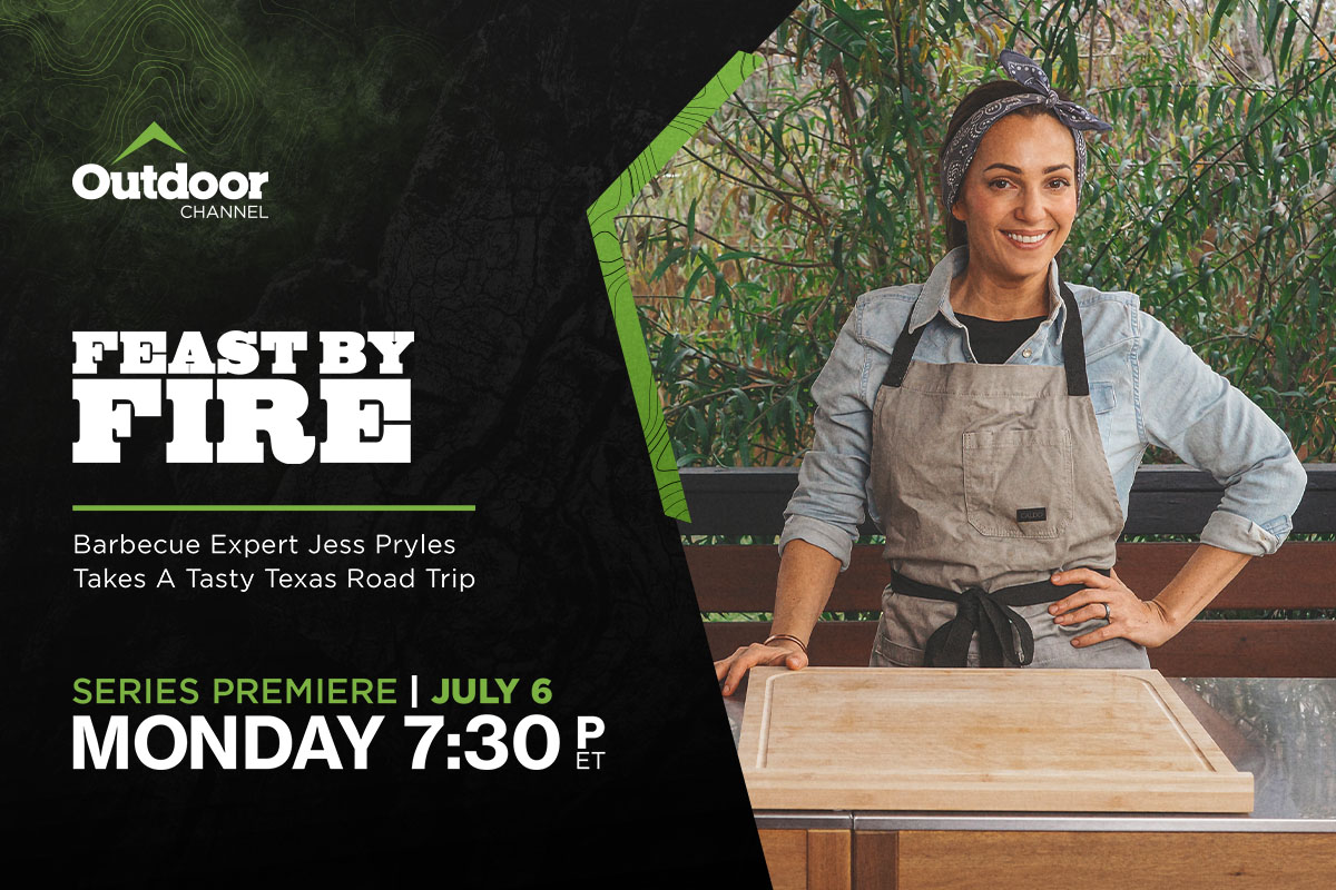 Chef in apron, standing outdoors behind cutting board