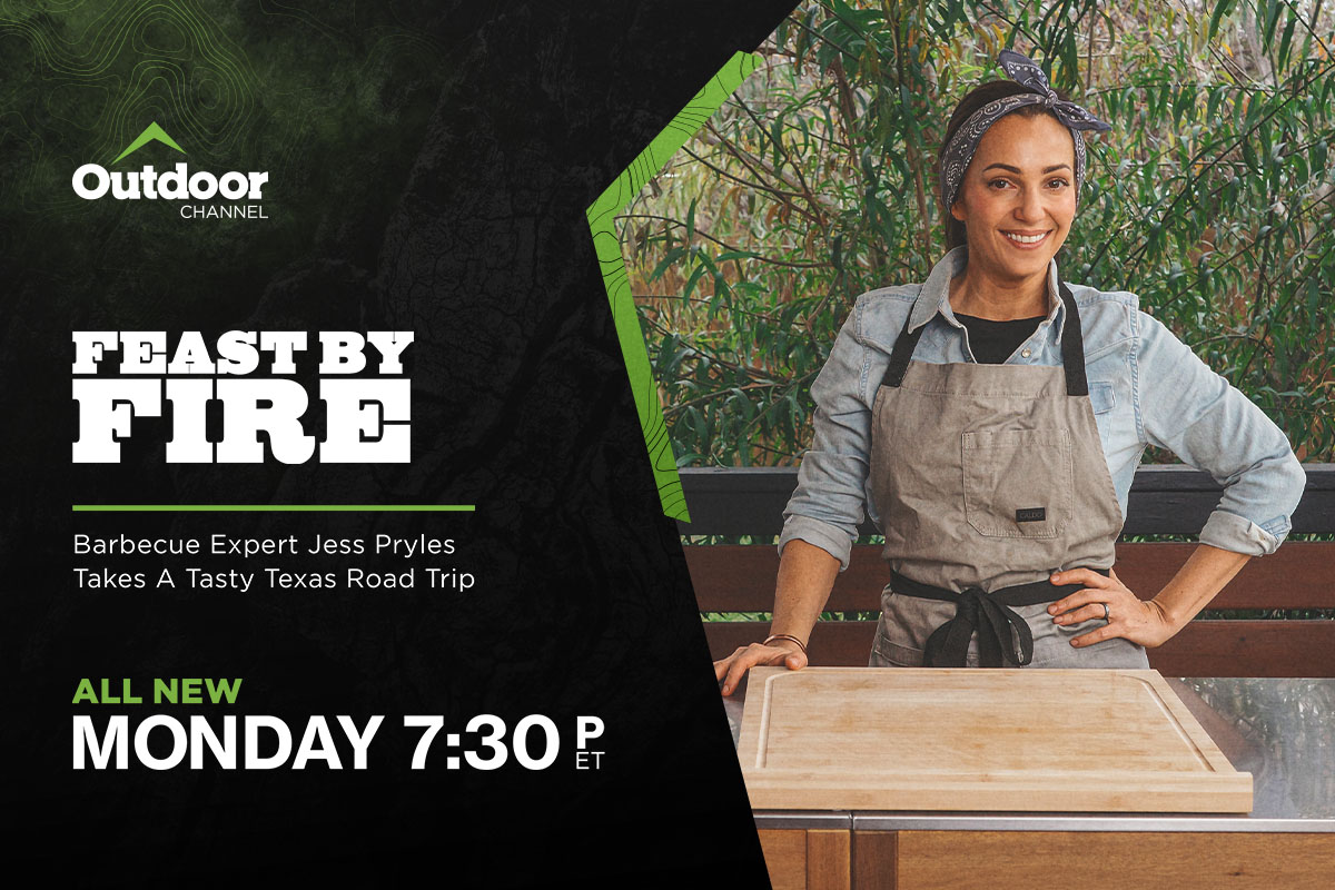 Chef in apron, standing outdoors behind cutting board