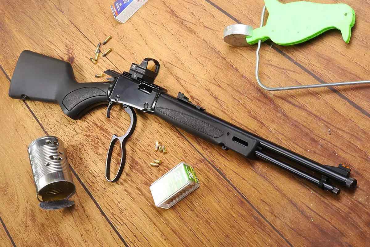 Black Henry rifle on wooden background with ammo and a shot tin can beside it
