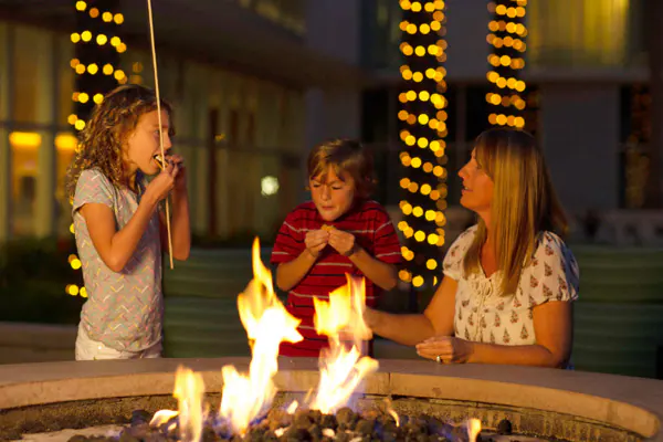 A family of three enjoys s'mores by a fire pit at Loews Sapphire Falls Resort at Universal Orlando.