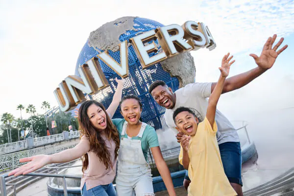 Family photo of everyone smiling wiht hands extended in front of the Universal globe outside of Universal Studios Florida.