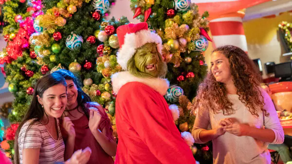 Guests meet and laugh with the Grinch dressed in a Santa costume during the holidays at Universal.