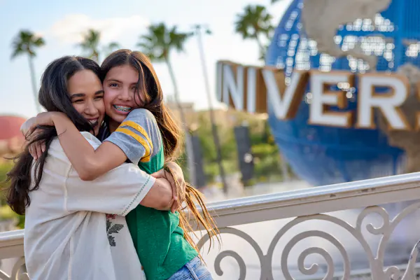A mother and daughter hugging and smiling in front of the iconic Universal globe.