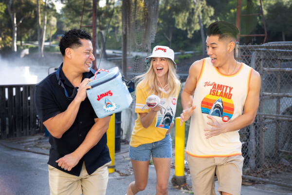 Three friends laughing and playing around with their JAWS 50th Anniversary Merch at Universal Studios Hollywood.