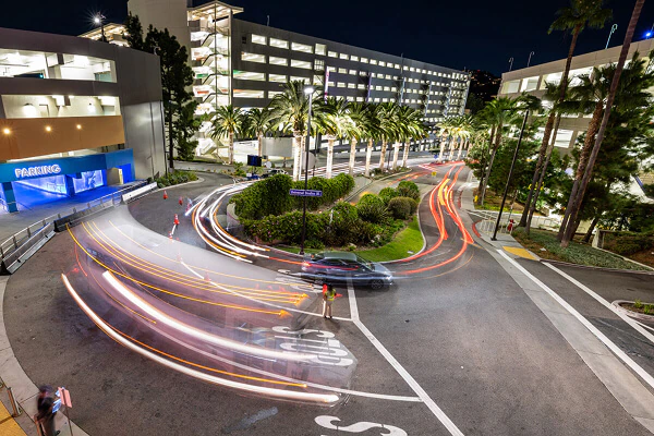 The front entrance of the parking garage to Universal Studios Hollywood with cars passing by, captured with motion blur.