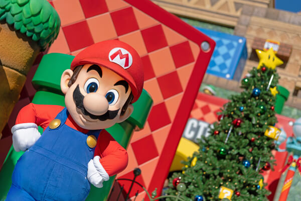 Mario posing with a Christmas tree in the background in Super Nintendo World™ at Universal Studios Hollywood